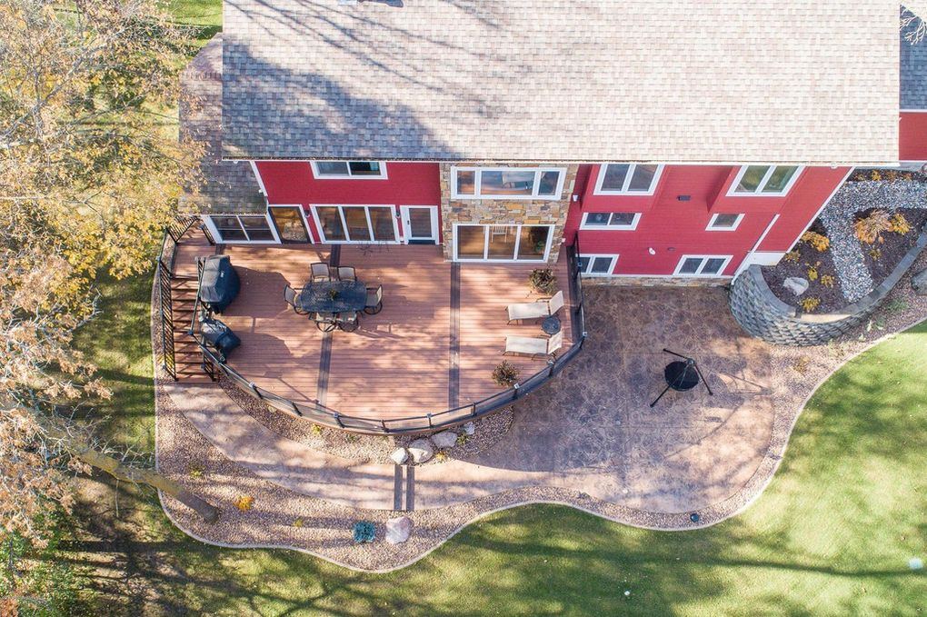 Curved composite deck with glass railing and stone accents on custom home in Fergus Falls, MN, supplied by Lakeside Lumber