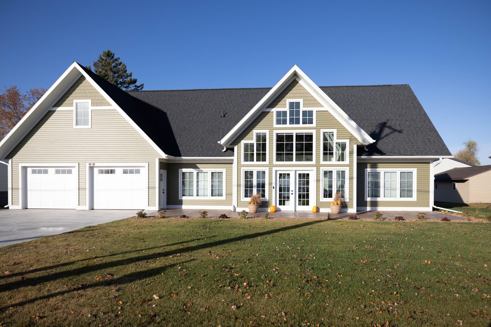 Custom home with olive vinyl siding, white trim, and large gable windows in Battle Lake, MN, supplied by Lakeside Lumber