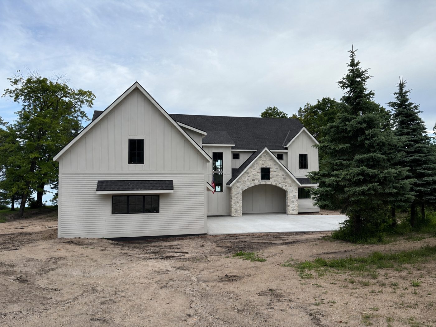 Completed custom home on Otter Tail Lake with stone archway and board and batten siding — materials from Lakeside Lumber