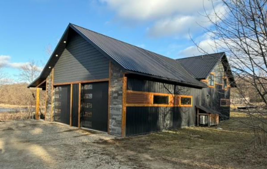 Custom shouse with dark steel siding, stone accents, and cedar trim built by Hasling Construction near Pelican Rapids, MN with materials from Lakeside Lumber